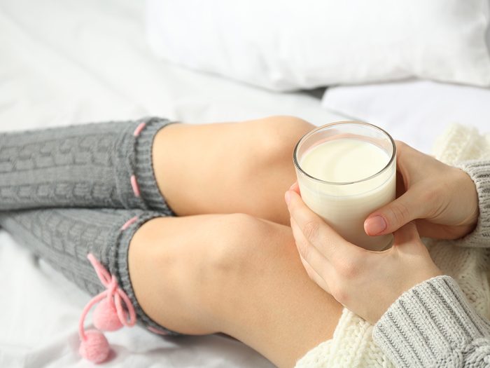 Calcium, woman lying in bed with cup of milk