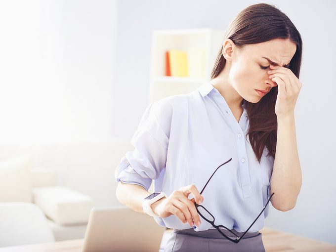 Woman holds her head because of a painful migraine