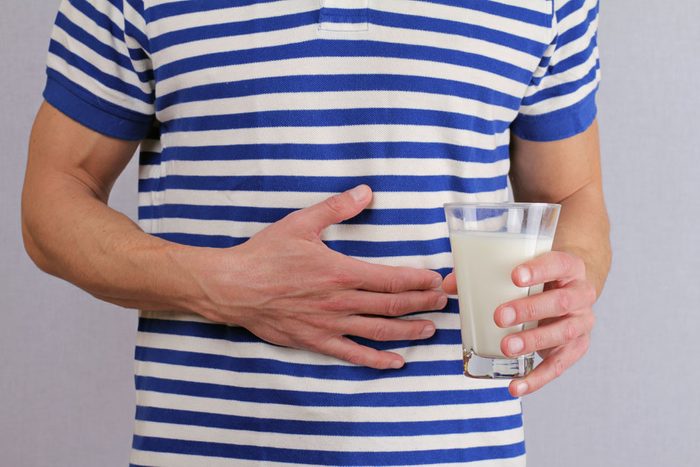 Lactose intolerant man holds his stomach and a glass of milk
