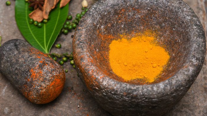 turmeric being crushed with mortar and pestle