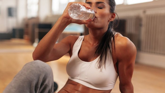 woman drinking water after a hard workout