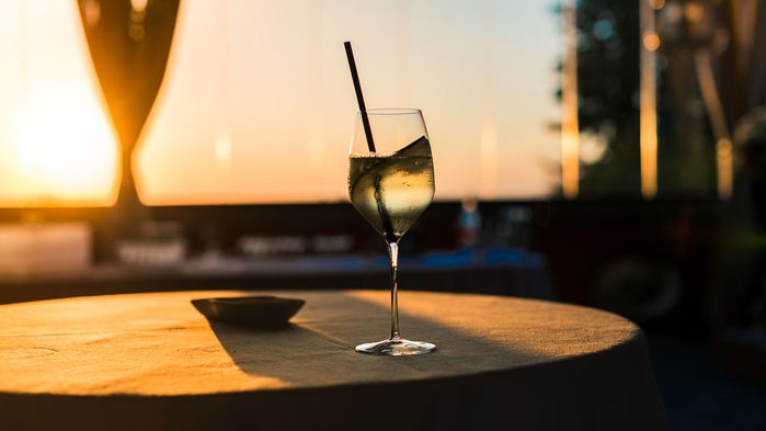A glass of wine on a restaurant patio table at sunset
