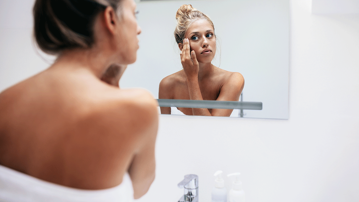 Dark Spots, woman looking at her face in the mirror