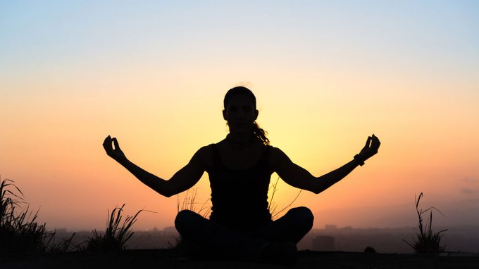common autoimmune diseases in Canada, a woman doing the yoga lotus pose at sunset