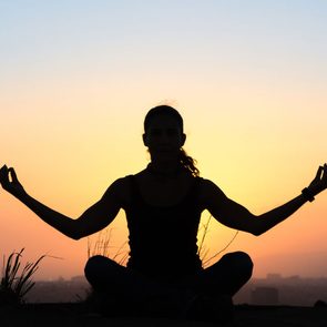 common autoimmune diseases in Canada, a woman doing the yoga lotus pose at sunset
