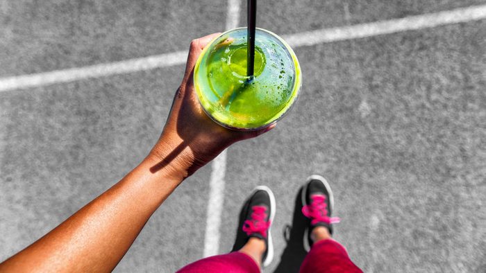 What to eat before a run, a woman doing a "from where I stand" selfie showing running shoes and a green smoothie
