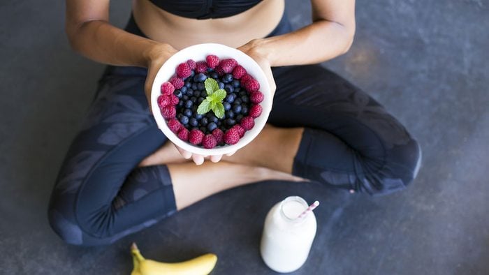 foods for a healthier heart, a woman who just worked out is sitting and eating a bowlful of berries