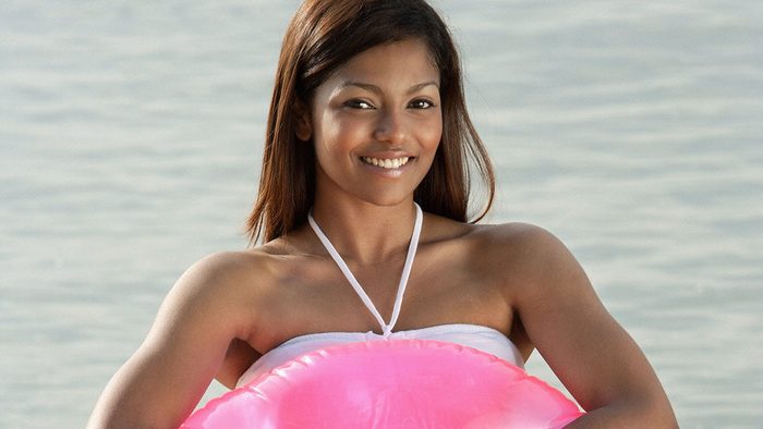sunscreen myths dark skin, woman with dark skin on the beach