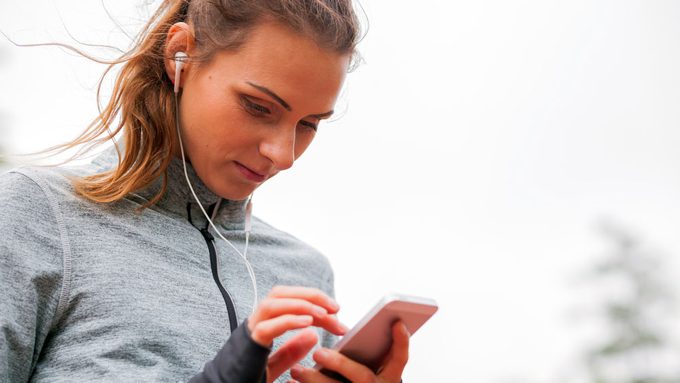 Canadian Workout Playlist, woman setting her songs on her phone before a run