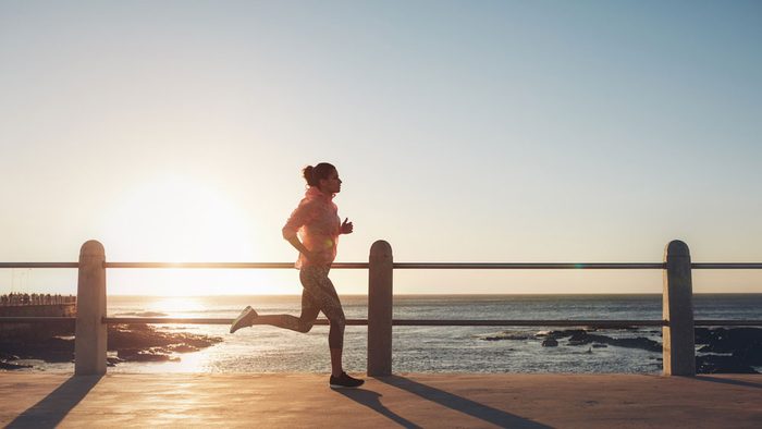 staying motivated in summer, a woman runs along a boardwalk