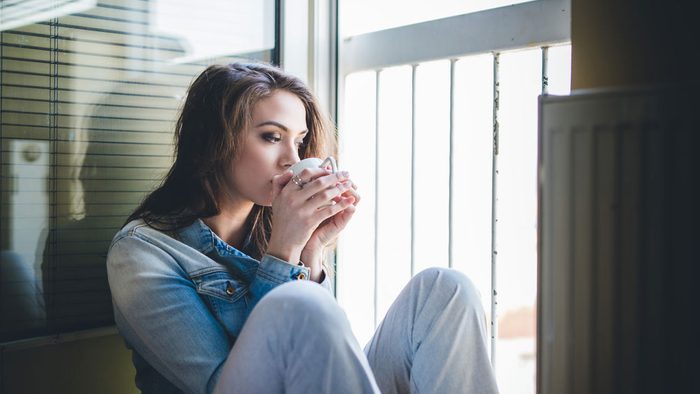 home giving you anxiety, woman drinking coffee on her balcony
