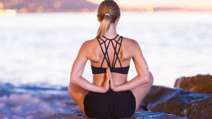 wellness getaways breathe meditation, a woman meditating on the beach