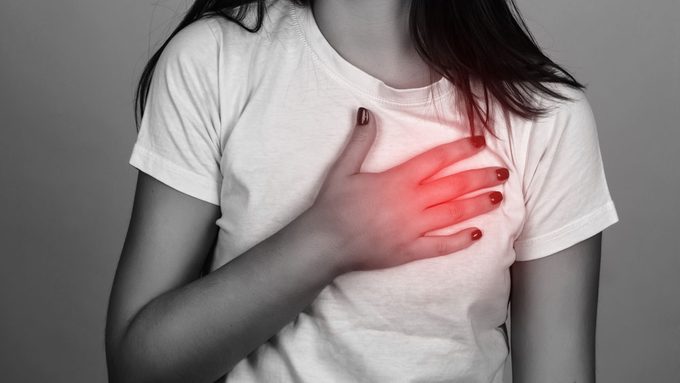 heart attack symptoms for women, a young woman holding her chest