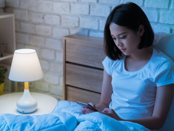 blue light, woman in bed looking at her phone