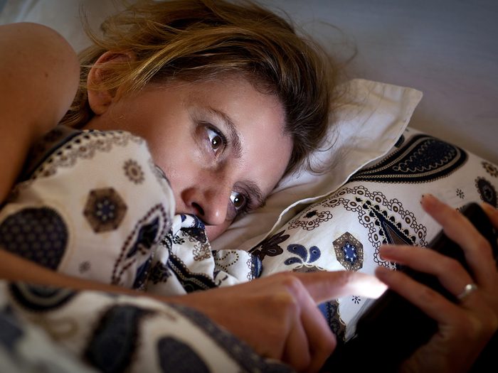 Aging, Woman checking phone from bed