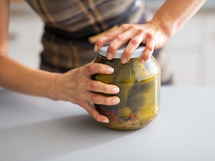 Aging, woman trying to open jar of pickles