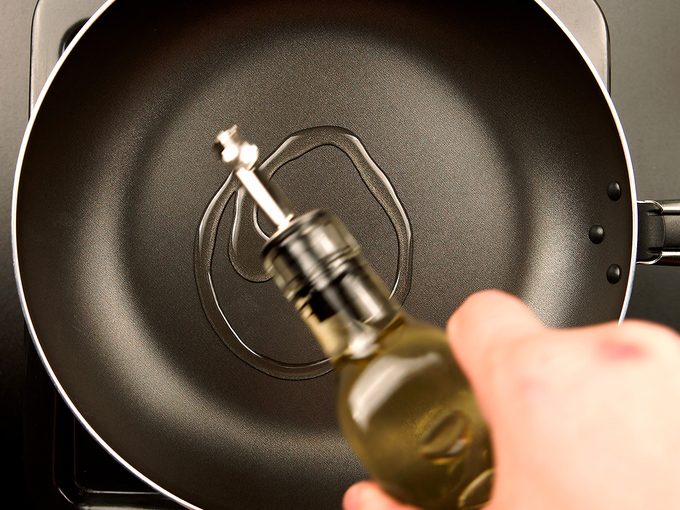 Cooking oil being drizzled into a frying pan