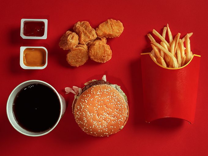 Fast food flatlay that includes chicken nuggets, coke, a burger and fries