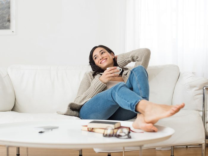 Green tea, woman relaxing on the couch with green tea in mug