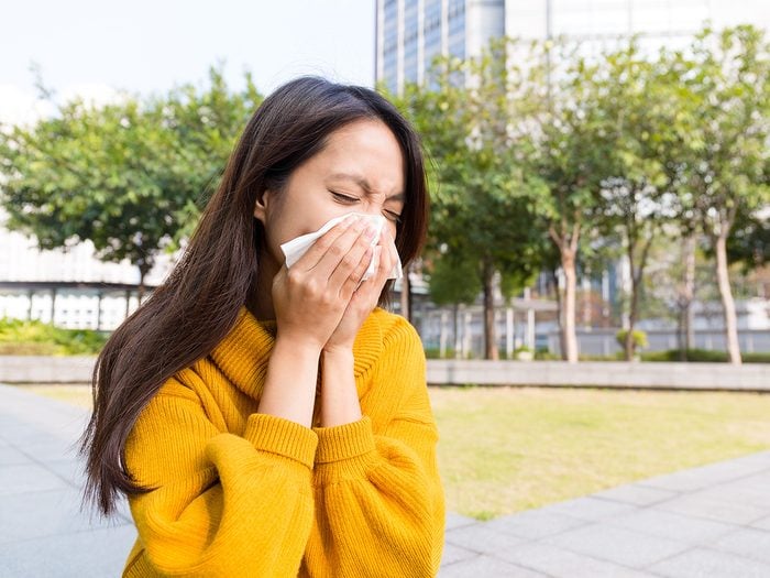 Green tea, Young woman sneezes into a tissue outdoors