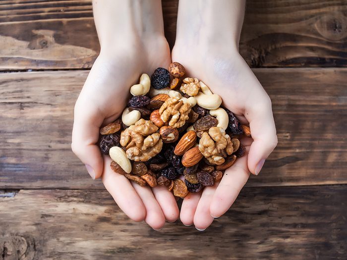 Health myth, a woman holds a handful of nuts and dried fruit over a wooden table
