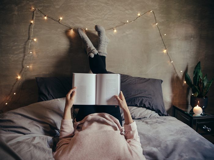 Health myth, a woman reads a book in her dimly lit bedroom