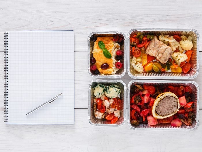 Healthy eating, An open notebook ready for meal planning and four meals in containers