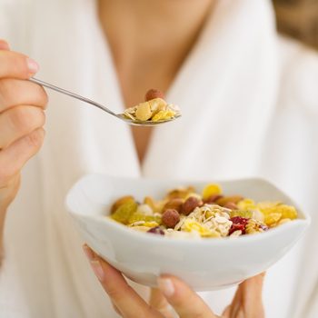 High cholesterol, woman in robe eating bowl of nut cereal