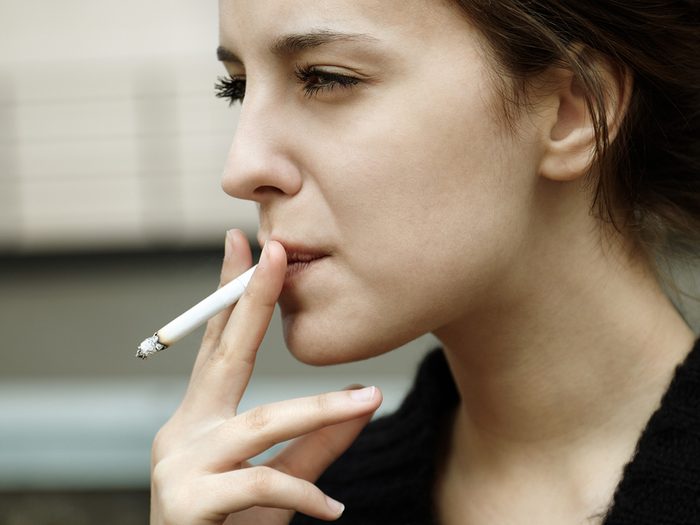 High cholesterol, young woman smoking outside