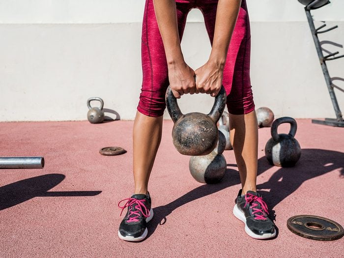 Female athlete with kettlebell working out in outdoor gym