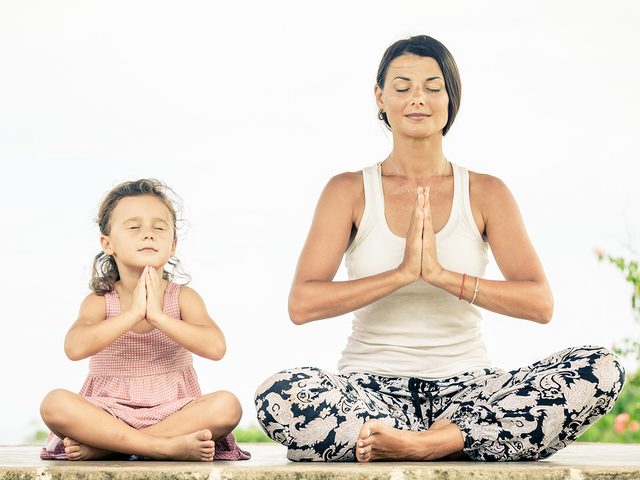 Meditation, woman meditating in a crossed legged position with her daughter