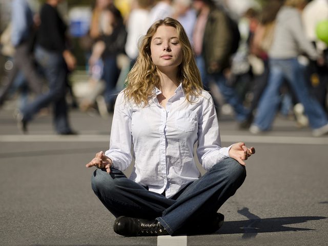 Meditation, woman meditating in the middle of a busy street