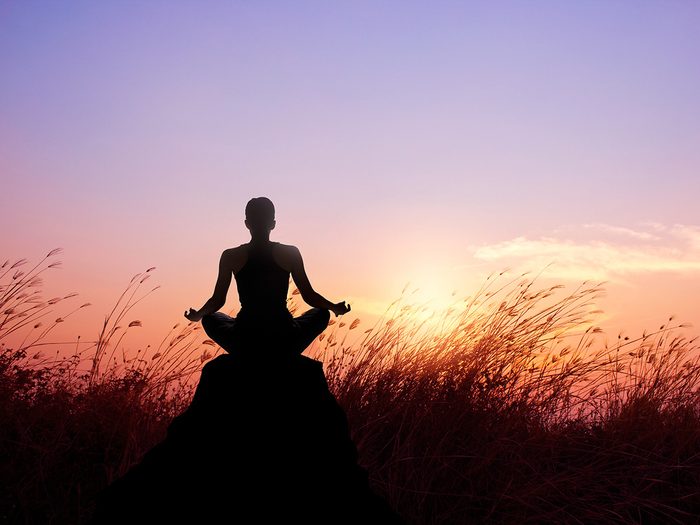 Meditation, Woman meditating at sunrise in a field 