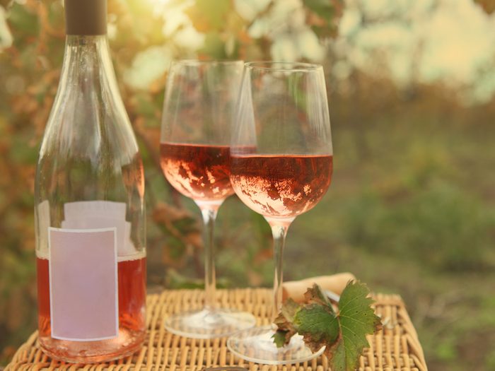 Pink wine bottle and glasses in vineyard