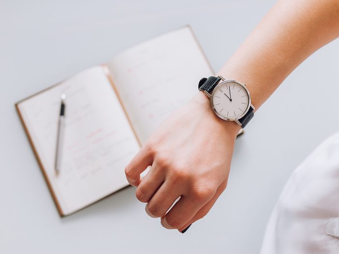 Productivity, close-up of woman's hand and watch above a notebook and pencil