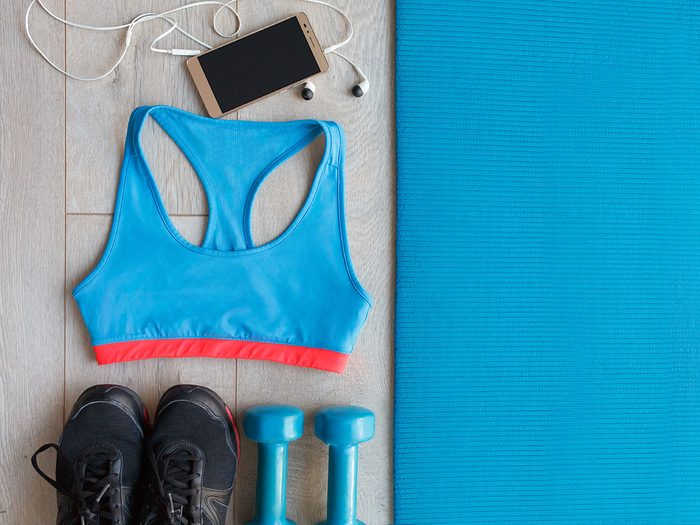 Productivity, a blue yoga mat, blue gym bra, cell phone with earbuds, blue weights and black runners
