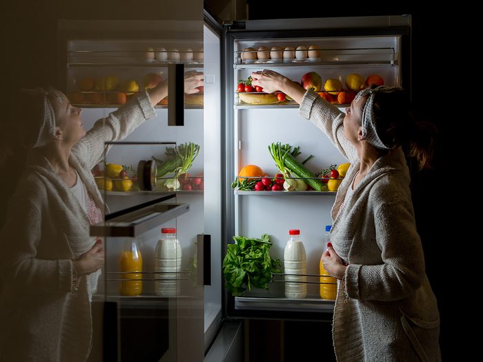 Weight Los Myths woman snacking at fridge late at night