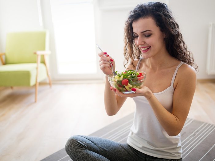 Weight loss myths, woman on yoga mat eating salad