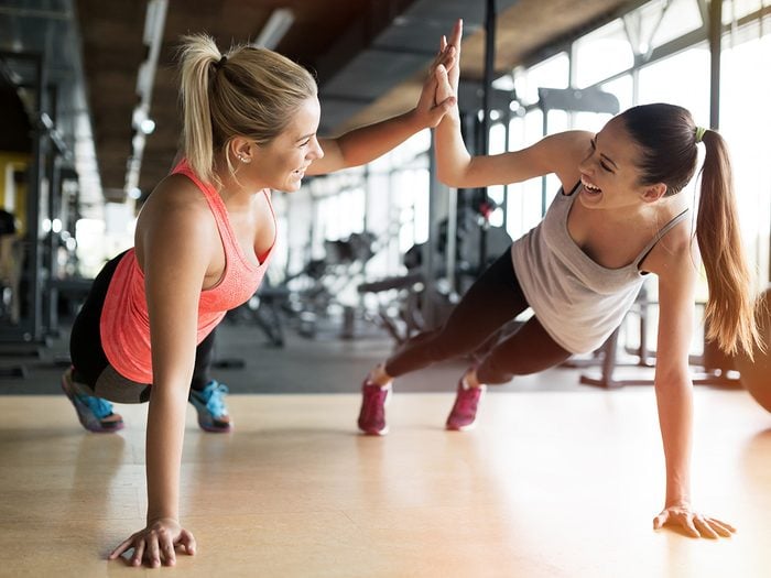 Happiness, two young women high five as they do planks at the gym