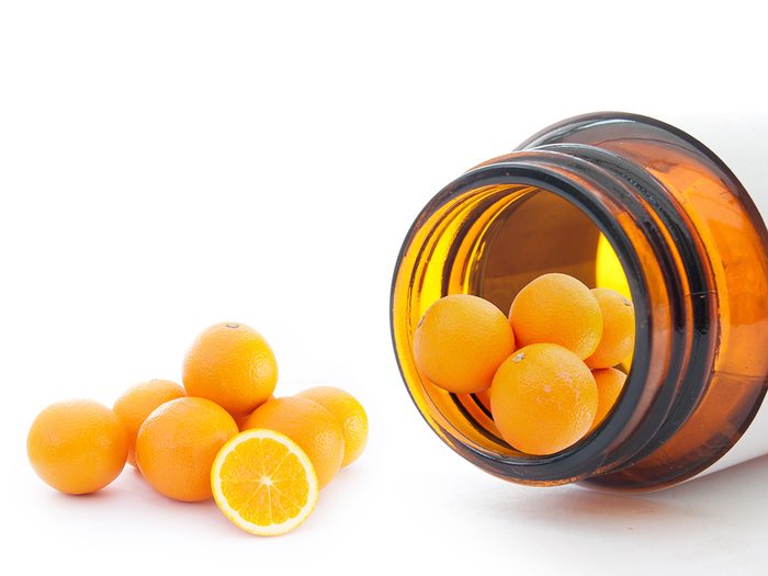 Biotin, vitamin C tablets that look like mini oranges roll out of a pill bottle