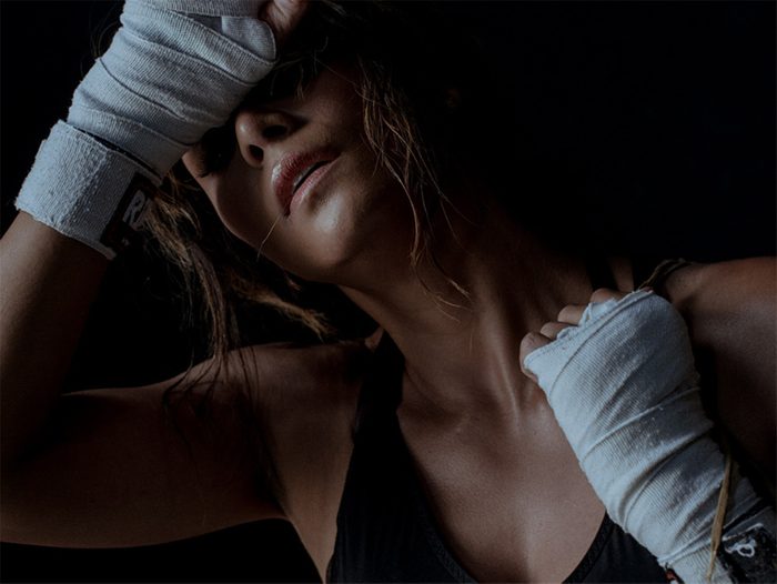 Halle Berry wipes her sweaty forehead with her hands in boxing wraps