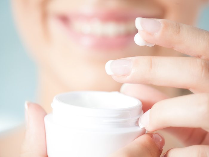 Health trends, a woman dipping her fingers into a jar of face cream