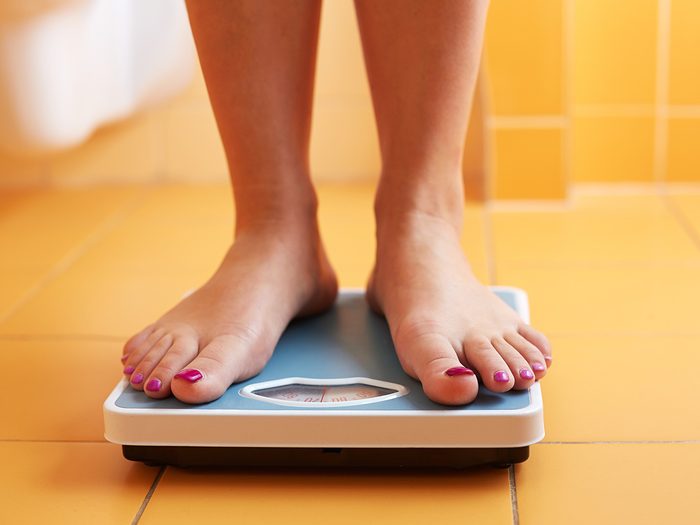 Health snacks, woman standing on scale to weigh herself