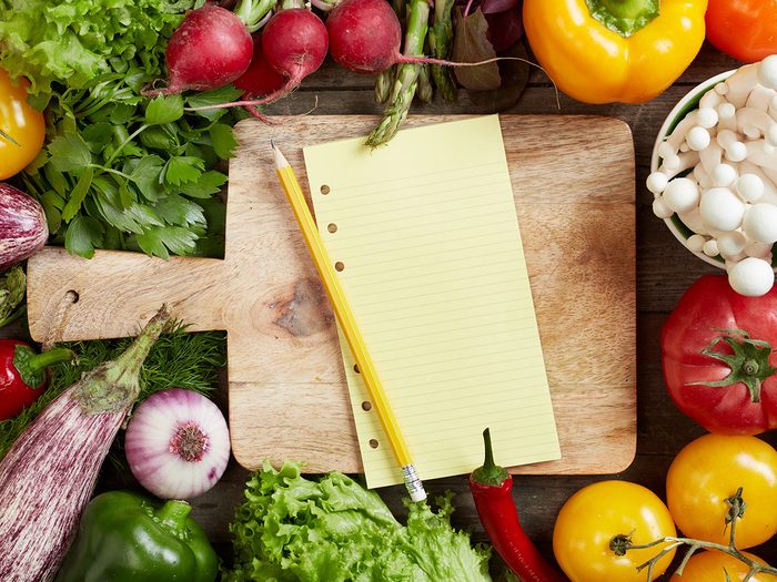 How to eat healthy, blank grocery list and pencil surrounded by vegetables