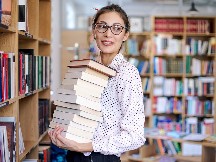 Intelligence, woman in library holding stack of books