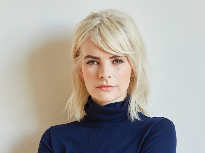 Kelly Oxford with bleach blonde hair wearing a blue turtleneck