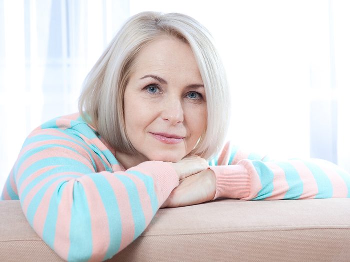 Menopause symptoms, middle-aged woman rests on couch