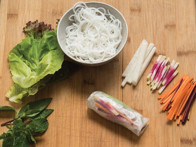 Assembling rice paper rolls with raw veggies and rice noodles
