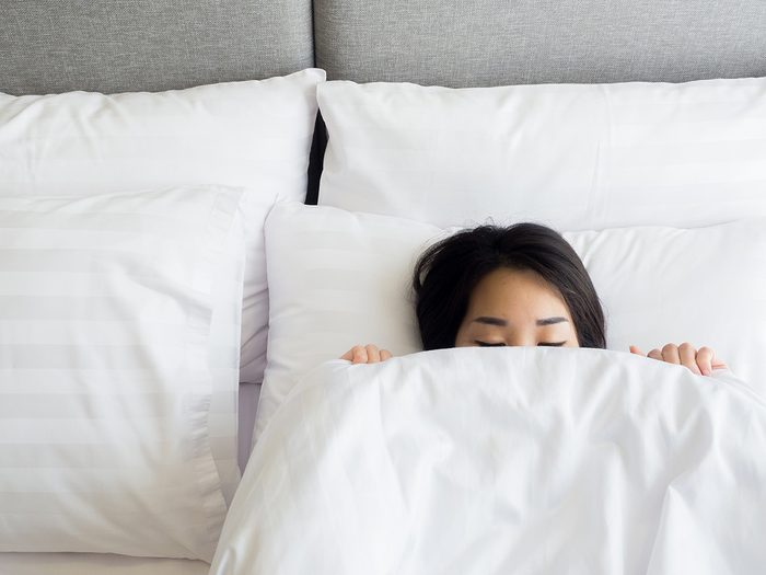Weight gain, woman lying in bed with just the top of her head peeking out