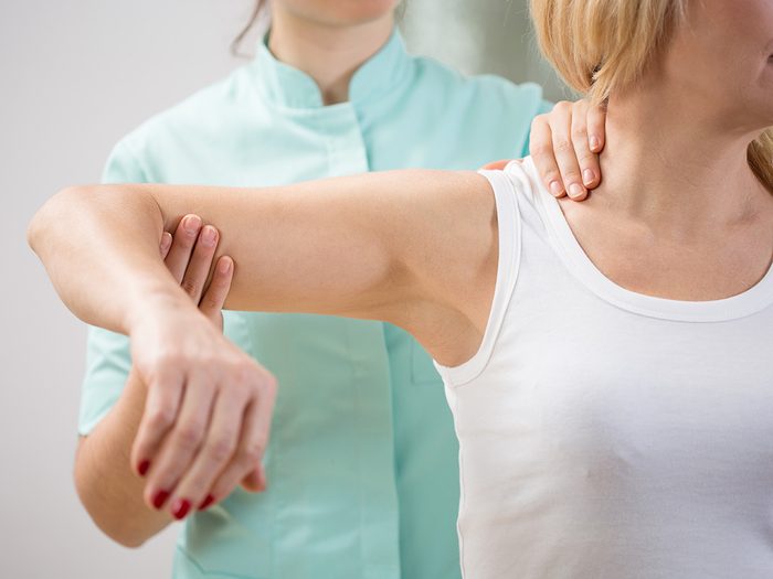 Weight gain, therapist moves woman's stiff arm and shoulder